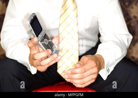 Mid section view of a businessman holding a mobile phone REF : 10016 122 CRUSC Crédit obligatoire : Stuart Cox/sem - Allemand Banque D'Images