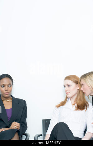 Businesswoman assis à côté de deux femmes d'affaires et de whispering REF : 10020 130 CRUSC Crédit obligatoire : Staurt Sem - Allemand / Cox Banque D'Images