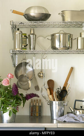Détail de cuisine avec des pots en acier inoxydable et des ustensiles sur étagères métalliques. Banque D'Images