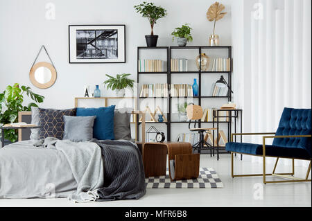 Un lit douillet au milieu d'un appartement moderne et lumineux avec des meubles d'intérieur et décoration, espace de travail avec bibliothèque et les plantes Banque D'Images