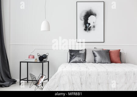 Chambre Simple et élégant intérieur avec des coussins d'argent sur un lit blanc debout contre un mur au moulage Banque D'Images