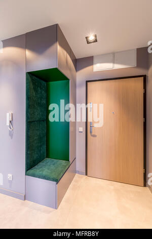 Hall d'entrée spacieux, simple à un appartement lumineux intérieur avec porte en bois et un fauteuil de velours vert, Banque D'Images