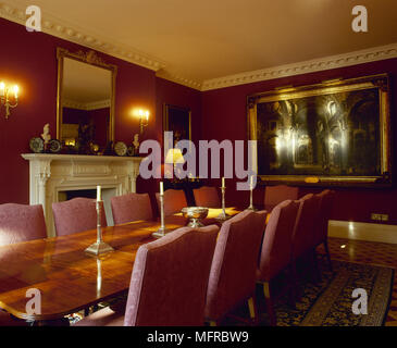 La salle à manger avec table à manger en bois, fauteuils, cheminée, une illustration et bougeoirs de mur éclairé. Banque D'Images