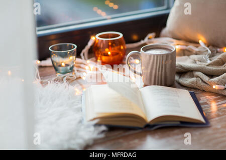 Livre et du café chaud ou cchocolate on window sill Banque D'Images