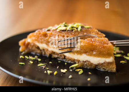 Dessert traditionnel turc Ekmek Kadayifi / Le Pudding sur une surface en bois. Banque D'Images