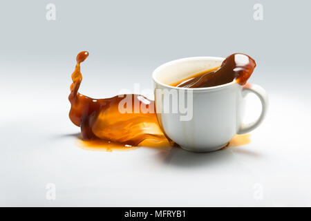 Tomber et d'éclaboussure d'une tasse de café sur un fond blanc. Banque D'Images