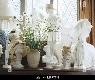 Les chiffres blancs et statues porter un chapeau des chrysanthèmes blancs dans la fenêtre à côté de la collection vase en céramique céramique plâtre Banque D'Images