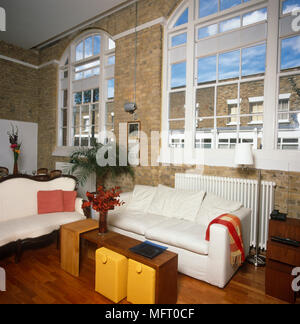 Deux canapés blancs autour de table en bois dans un style loft avec des murs en briques Banque D'Images