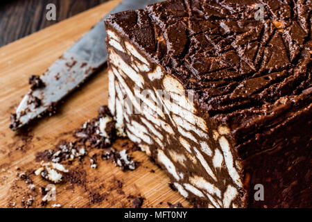 Gâteau au chocolat et de biscuits de la mosaïque à l'aide d'un couteau sur la surface en bois. Concept de dessert. Banque D'Images