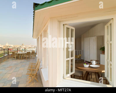 Extérieur de fenêtre ouverte d'appartement avec grand balcon salon et paysage de ville en arrière-plan Banque D'Images