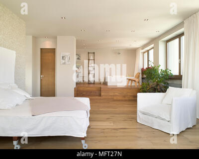 Chambre à coucher ouverte avec plancher en bois et un lit double avec des marches menant jusqu'à la salle de bain salon Banque D'Images