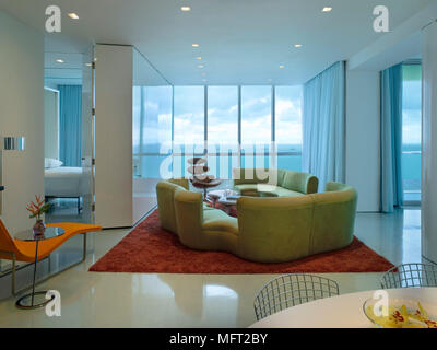 Un style rétro moderne, plan ouvert salon avec coin repas, d'un siège rembourré, tapis rouge, combinaison de designer en vue, coin salon, chambre à coucher Banque D'Images