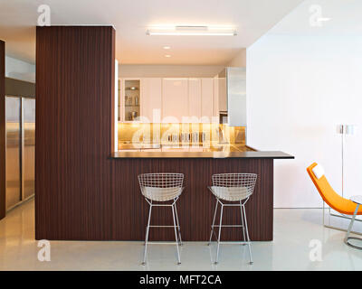 Une cuisine moderne blanc, bois bar de petit-déjeuner, Harry Bertoia wire tabourets, Banque D'Images