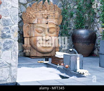 Baignoire encastrée en plein air sur le patio isolé de villa privée avec tête de Bouddha sculptée Banque D'Images