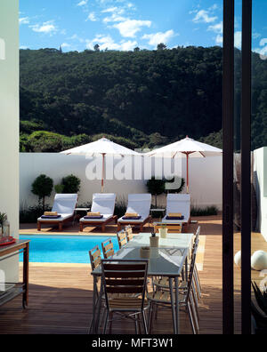 Une piscine extérieure avec terrasse fleurie des chaises longues avec parasols table et chaises Banque D'Images