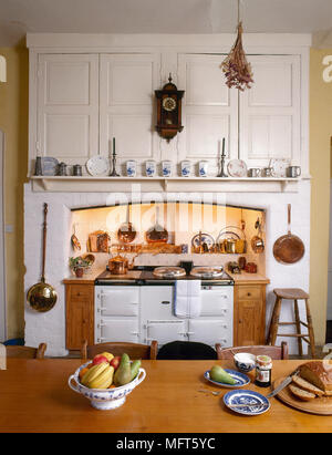 Une cuisine rustique avec table de ferme, blanc dans l'encoche, Aga, casseroles en cuivre Banque D'Images