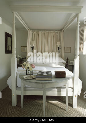 Table demi-lune au pied du lit à baldaquin peint dans un style champêtre chambre Banque D'Images