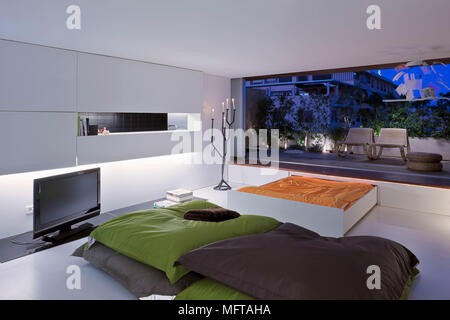 Coussins étage en face de la télévision grand écran dans cette chambre moderne avec porte ouverte à l'extérieur zone pontés Banque D'Images