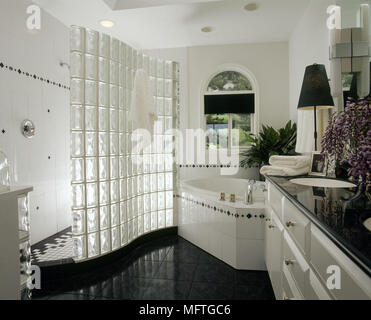 Salle de bains baignoire d'angle moderne blanc douche à l''écran de douche en briques de verre intérieur carrelage noir brillant reflet monochrome douches salles Banque D'Images