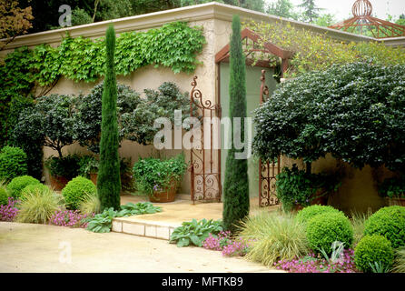 Coglizer jardin avec une plantation de Cupressus sempervirens Buxus sempervirens, ÔSuffruticosaÕ, Carex morrowii, géranium x cantabrigiense, Rhododendron Banque D'Images