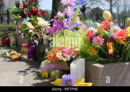 Fleurs en plastique colorés placés dans un ciment à l'honneur perdu des êtres chers. Banque D'Images