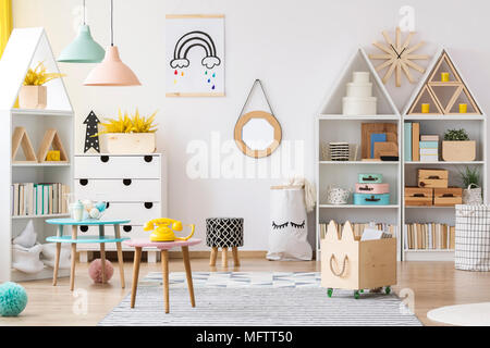 Miroir dans le cadre en bois accroché au mur à l'intérieur chambre blanche pour les enfants avec des livres et des jouets Banque D'Images