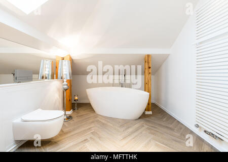 Blanc, moderne salle de bains grenier intérieur avec une baignoire en céramique, ovale, de chauffage mural et de poutres apparentes Banque D'Images