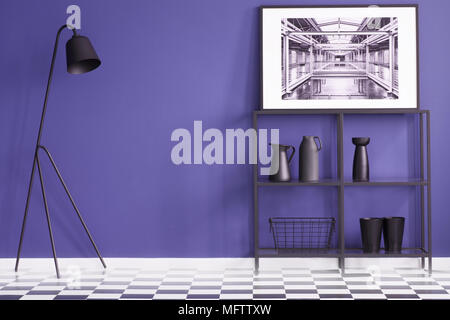 La salle de séjour avec un mobilier noir debout sur un sol en damier et une affiche d'une usine de l'intérieur. Photo réelle Banque D'Images