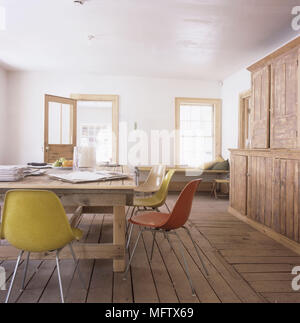 Table à manger en bois rustique avec des chaises en plastique jaune et orange Banque D'Images