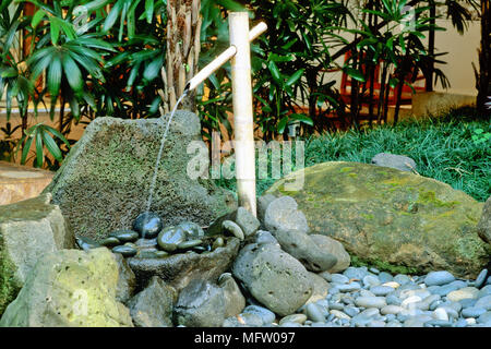 Un élément d'eau en bambou dans un jardin de style japonais Banque D'Images