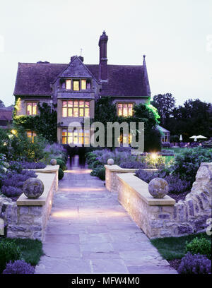 Vue extérieure de l'Hôtel Restaurant Saison Quartre jardin formel et illuminé à la tombée de la nuit. Banque D'Images