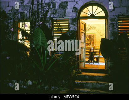 Vue du jardin en lit double salle à manger ouvert portes fenêtre en arc au-dessus de marches de pierre les portes les portes d'entrées volets éclairage chaud en soirée Banque D'Images