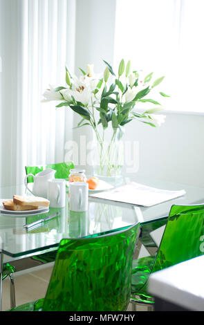 Toasts et de la marmelade sur table en verre avec chaises vertes en salle à manger Banque D'Images