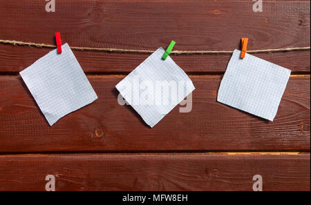 Trois feuilles blanches pour les notes suspendu à la corde avec clothespin sur le mur en bois. Maquette pour la conception. Banque D'Images