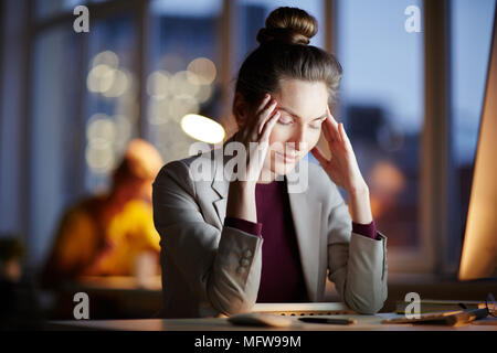 Portrait of a souligné businesswoman sitting at Office 24 et la fin de travail devant un ordinateur Banque D'Images