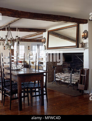 Lustre en fer forgé au-dessus de table et chaises en bois en style rustique salle à manger avec cheminée Banque D'Images