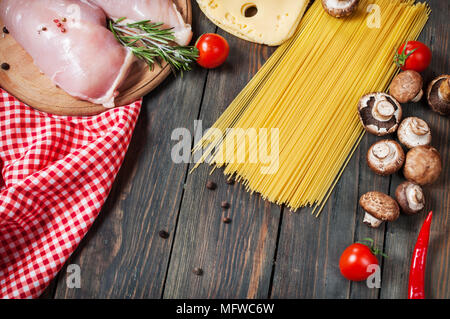 Ingrédients pâtes. Les tomates cerise, les pâtes spaghetti, filet de poulet et les champignons sur la table en bois Banque D'Images