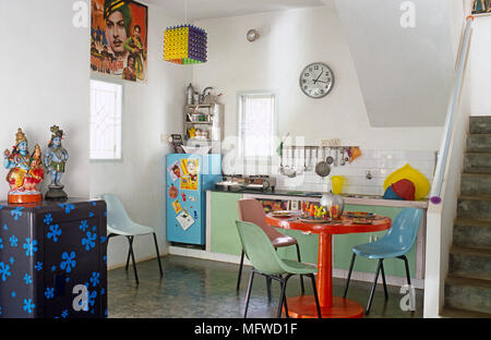 Des chaises en plastique coloré à round table de petit déjeuner dans une cuisine moderne Banque D'Images