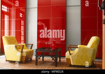 Paire de fauteuils capitonnés en face de l'autre d'un groupe ethnique à table dans un salon moderne Banque D'Images