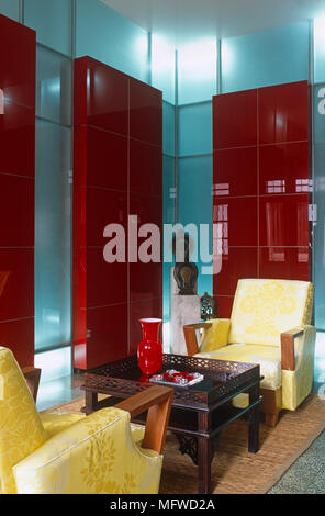 Paire de fauteuils capitonnés en face de l'autre d'un groupe ethnique à table dans un salon moderne Banque D'Images