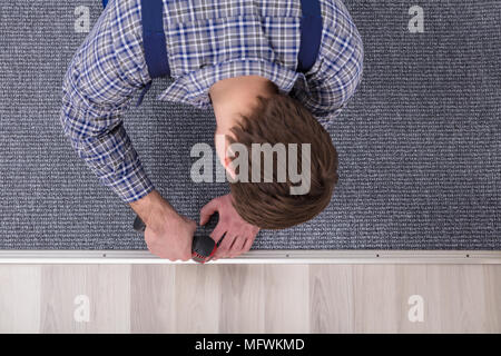 Close-up d'un ajusteur de Tapis Tapis gris la main de l'installation avec tournevis sans fil Banque D'Images