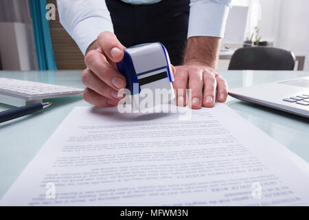 Close-up of a Businessman's Hand Stamping approuvé le document in Office Banque D'Images