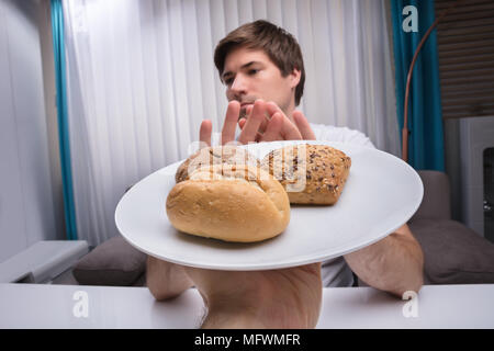 Close-up d'un jeune homme refusant des aliments cuits offerts par une personne Banque D'Images