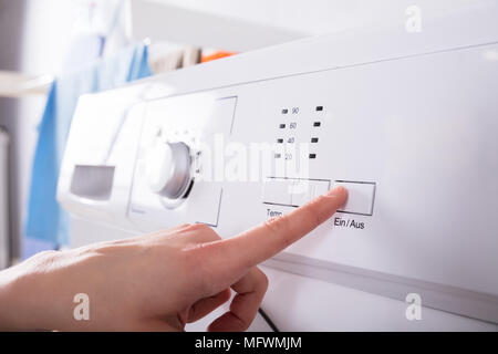 Close-up of a person's doigt appuyant sur le bouton de la machine à laver Banque D'Images