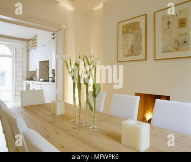 Tulipes unique en vases de verre sur table à manger en bois en face de l'incendie allumé Banque D'Images