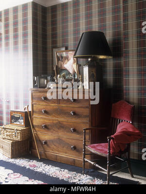 Commode en bois avec des ornements à côté de chaise avec tissus rouges et boîtes en osier Banque D'Images