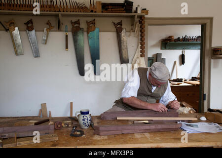 Ébéniste dans d'authentiques vêtements américain travaillant dans son atelier entouré de ses outils authentique dans la ville coloniale de Williamsburg en Virginie Banque D'Images