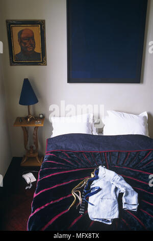 Lampe sur table de chevet à côté du lit double avec linge de lit rouge et bleu Banque D'Images