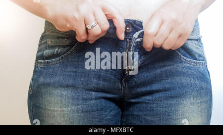 Un peu jeune femme essayant de surpoids de buton, son jean Banque D'Images