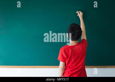 Asian boy écrit le conseil vert vide dans la salle de classe à l'école Banque D'Images